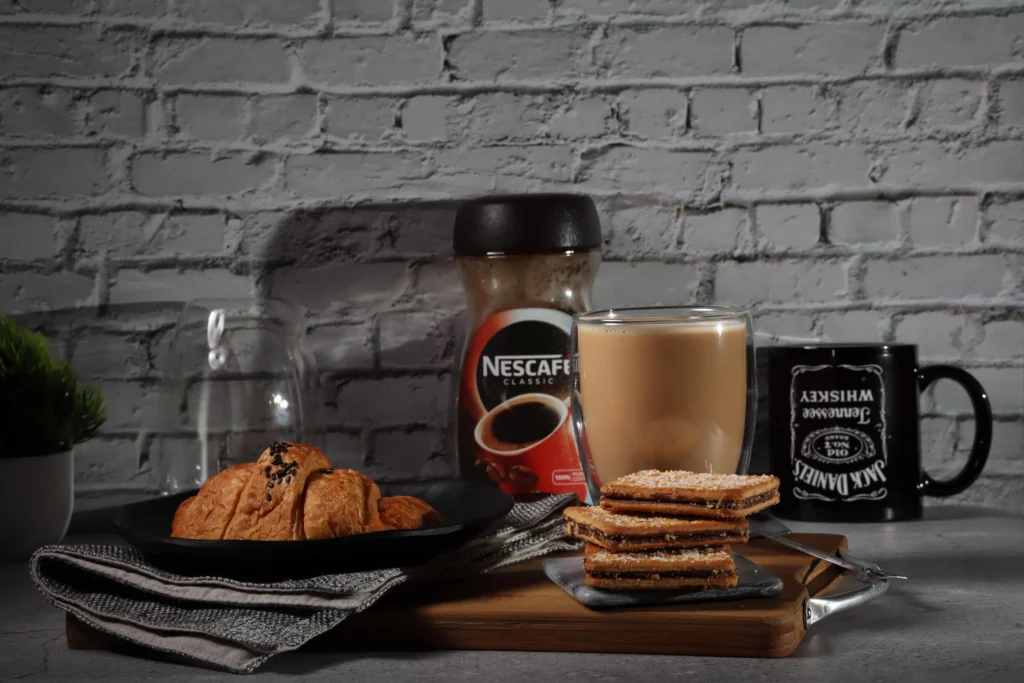 A collage of various Nescafe coffee products, including different flavored instant coffee sachets, coffee pods, and ground coffee canisters.